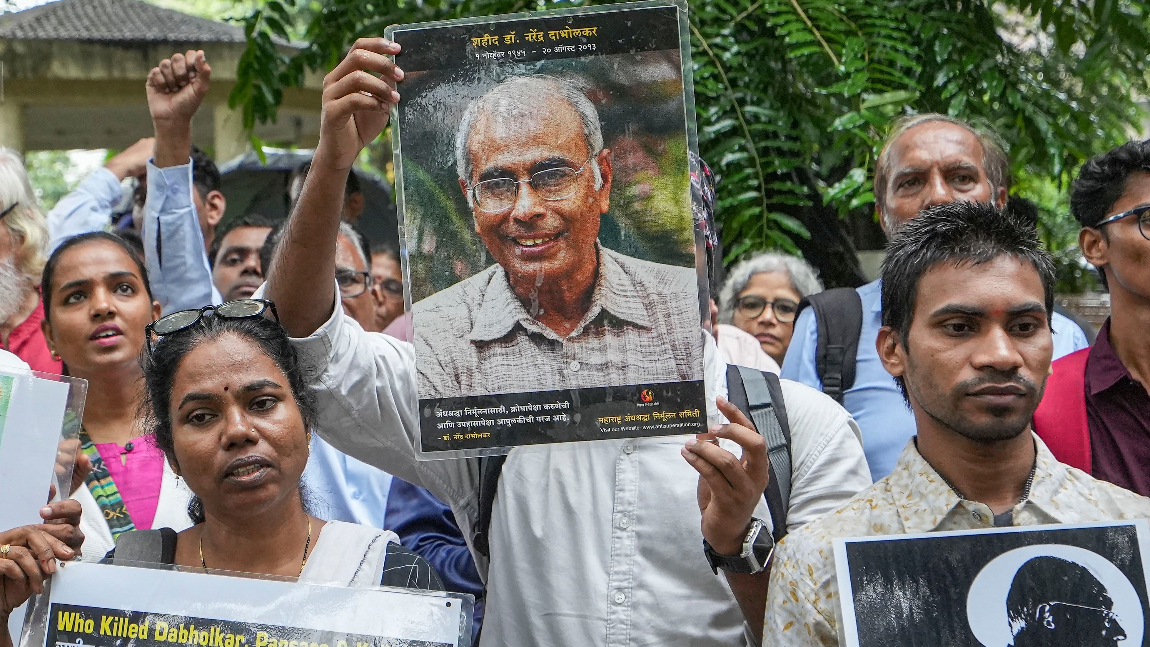 <div class="paragraphs"><p> File Photo: Maharashtra Andhashraddha Nirmulan Samiti member shows a portrait of Narendra Dabholkar.</p></div>