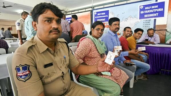 <div class="paragraphs"><p>Government employees on poll duty show their identification cards as they wait to cast their votes through postal ballot for Lok Sabha elections on May 4</p></div>