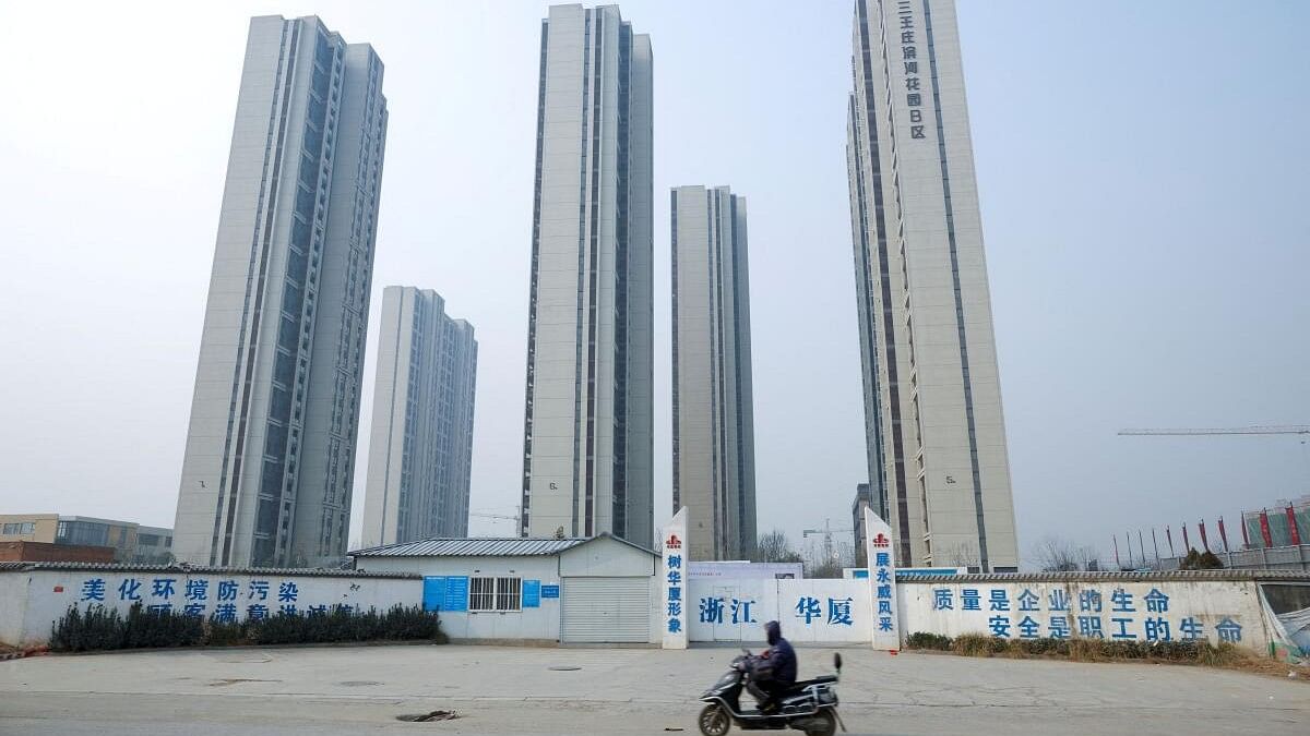 <div class="paragraphs"><p>A man rides a scooter past apartment highrises that are under construction near the new stadium in Zhengzhou, Henan province, China.</p></div>