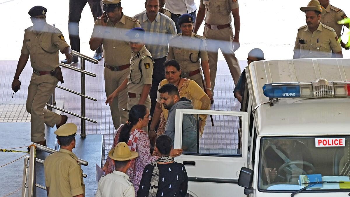 <div class="paragraphs"><p>Prajwal Revanna is being flanked by women officers.</p></div>