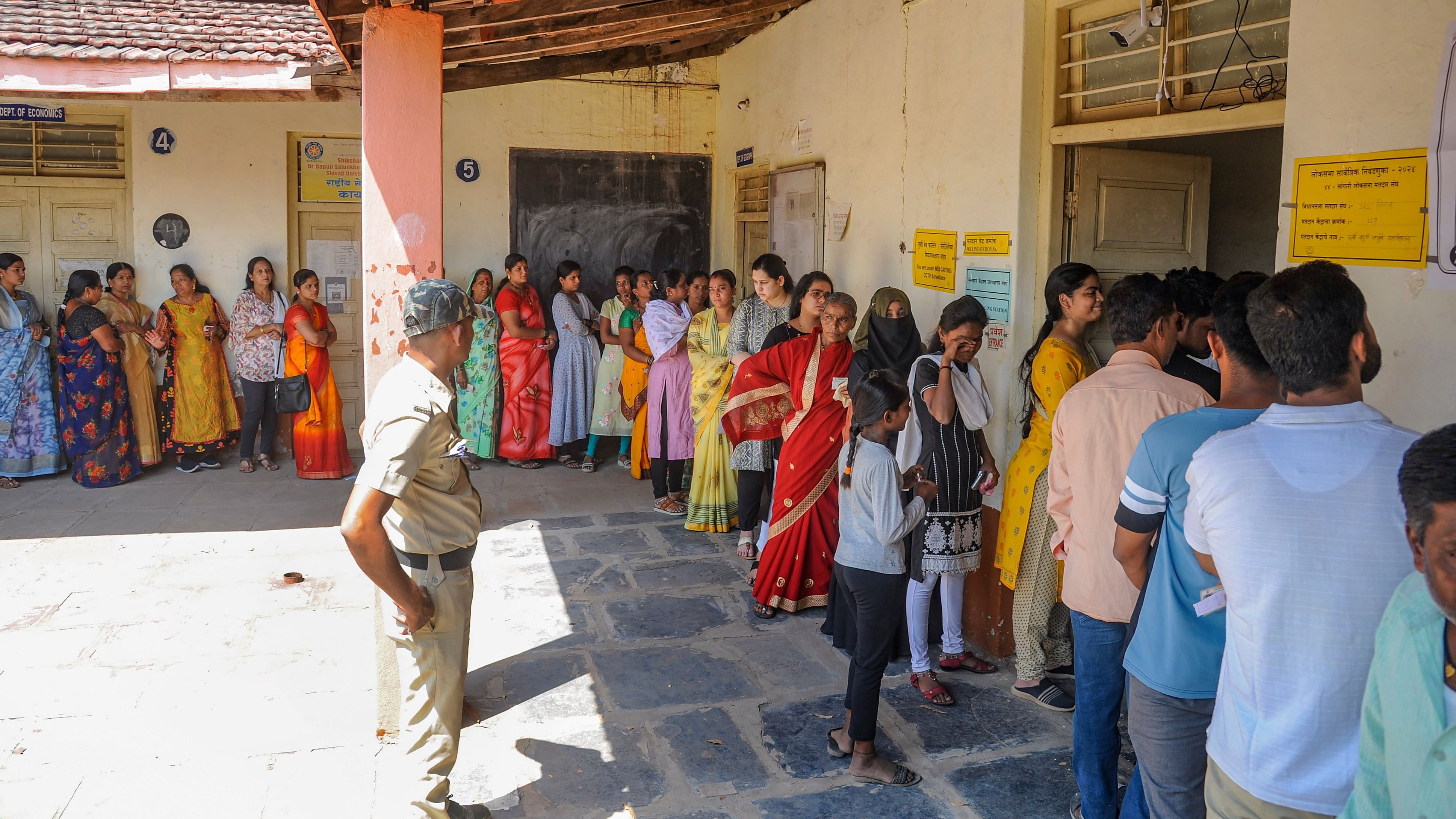 <div class="paragraphs"><p>A police officer stands guard as voters wait in a queue to cast their votes at a polling station, for the third phase of Lok Sabha elections, in Sangli, Tuesday, May 7, 2024. </p></div>