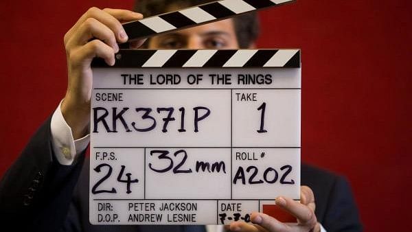 <div class="paragraphs"><p> gallery assistant poses for a photograph with a clapper board used in the filming of the Lord of the Rings.</p></div>