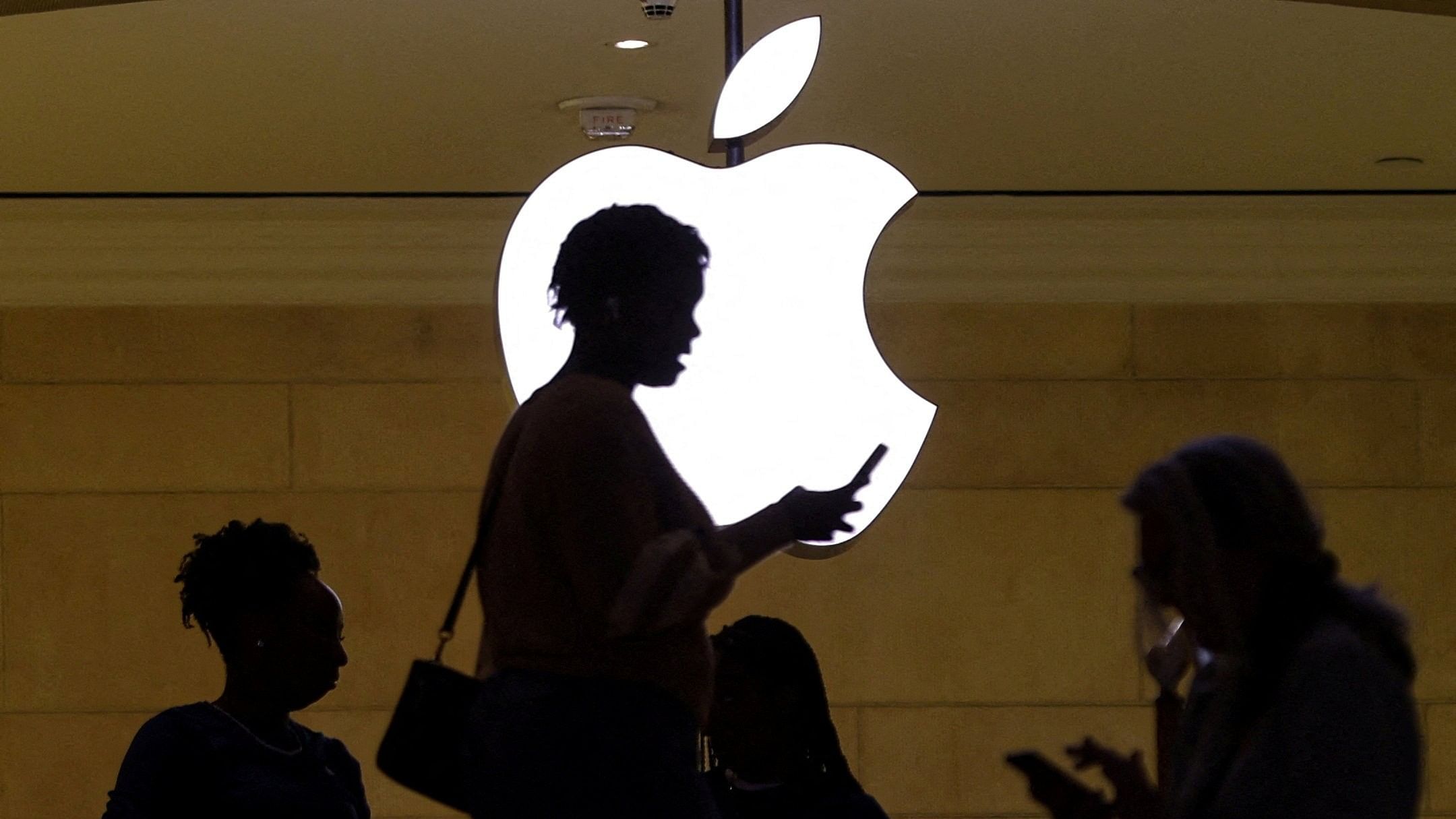 <div class="paragraphs"><p>A woman uses an iPhone mobile device as she passes a lighted Apple logo at the Apple store at Grand Central Terminal in New York City, US. </p></div>