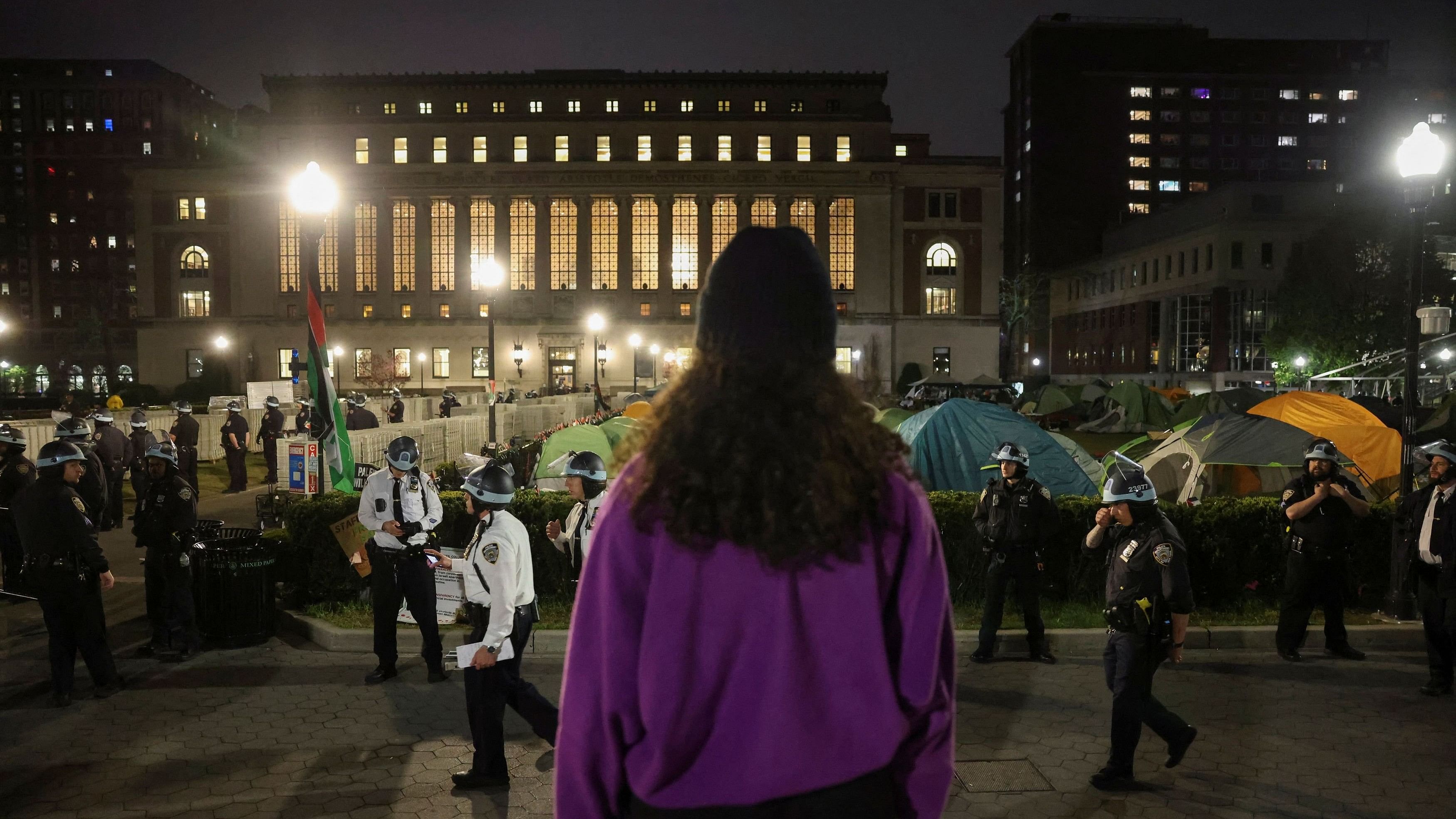 <div class="paragraphs"><p>A protestor looks on as the police stand guard near an encampment of protesters supporting Palestinians on the grounds of Columbia University, during the ongoing conflict between Israel and the Palestinian Islamist group Hamas, in New York City, US, April 30, 2024. </p></div>