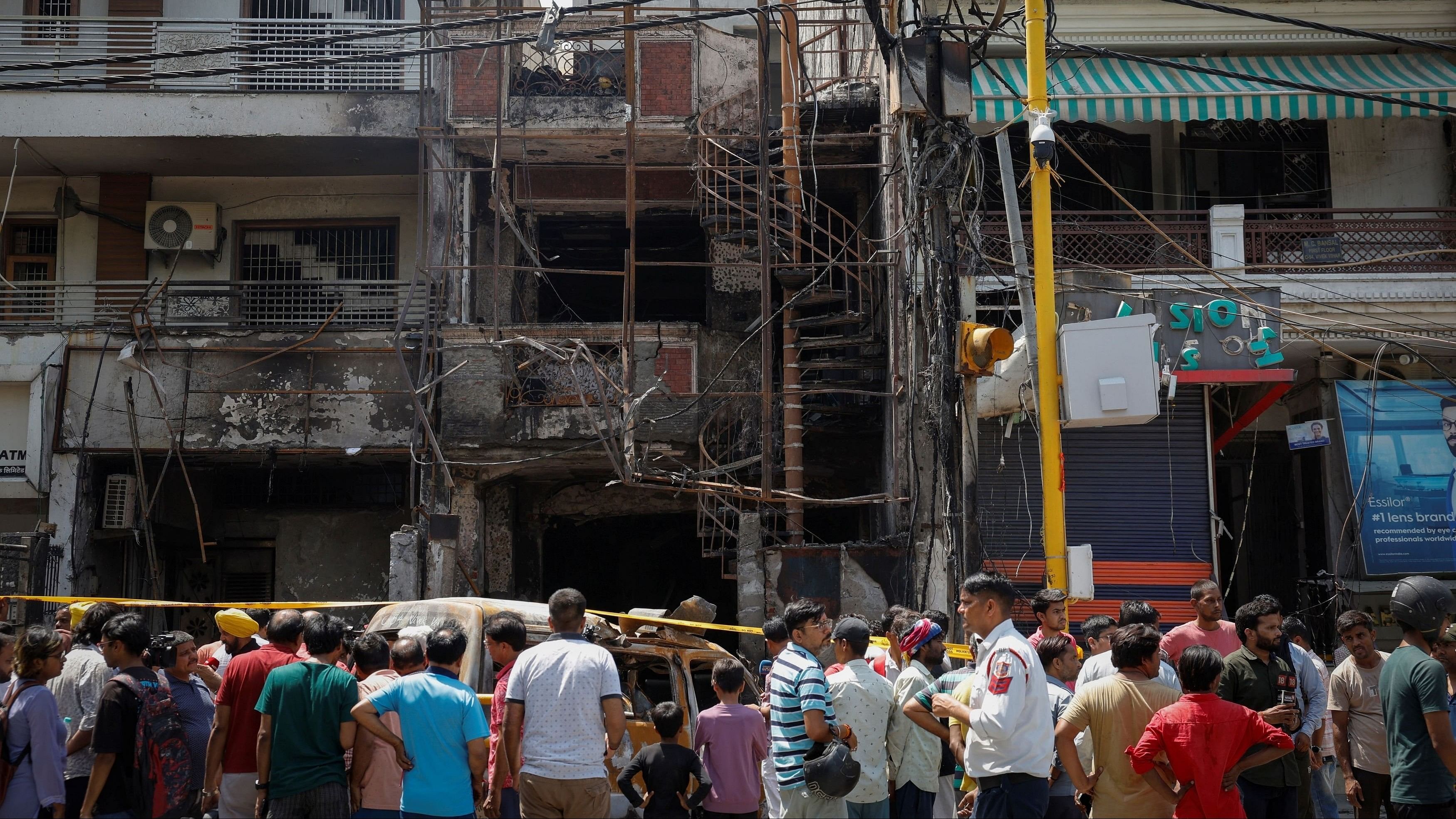 <div class="paragraphs"><p>People stand in front of a baby care hospital where several newborns died in a fire, in New Delhi.</p></div>