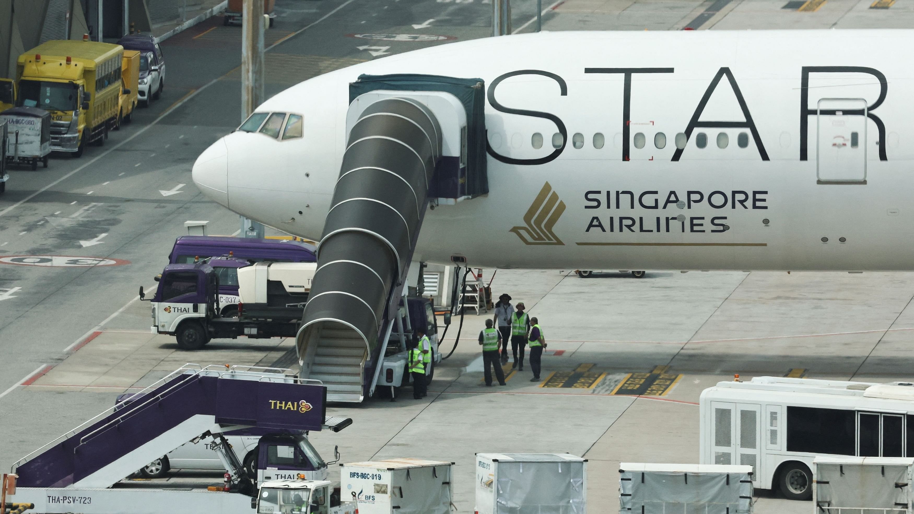 <div class="paragraphs"><p>Airport officials stand near the Singapore Airlines aircraft for flight SQ321 parked on the tarmac after an emergency landing at Suvarnabhumi International Airport, in Bangkok, Thailand.</p></div>