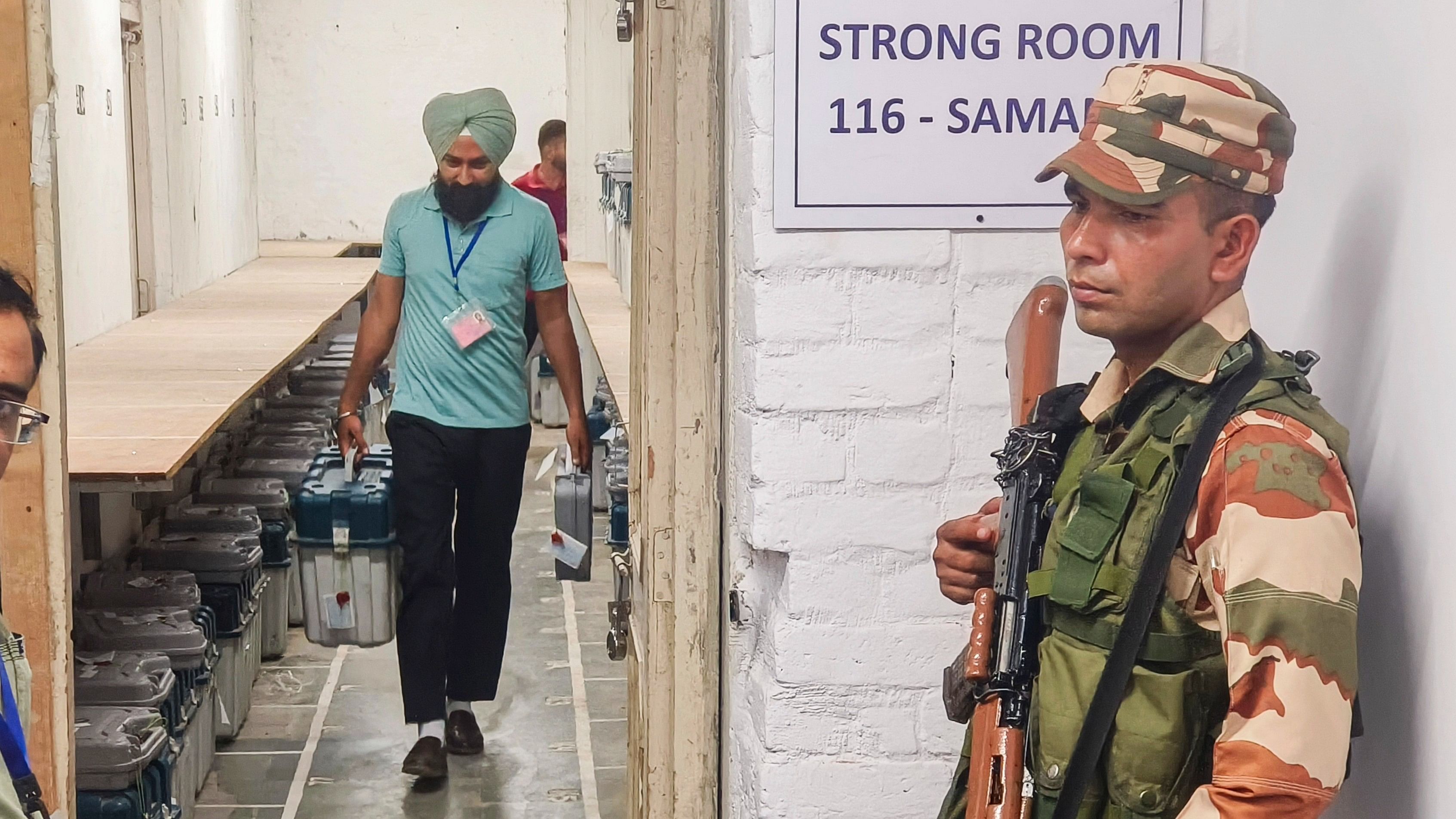 <div class="paragraphs"><p>A security official stands guard outside a strong room as a polling official leaves with the election material for his respective polling station on the eve of the seventh phase of Lok Sabha polls, in Patiala on Friday.</p></div>