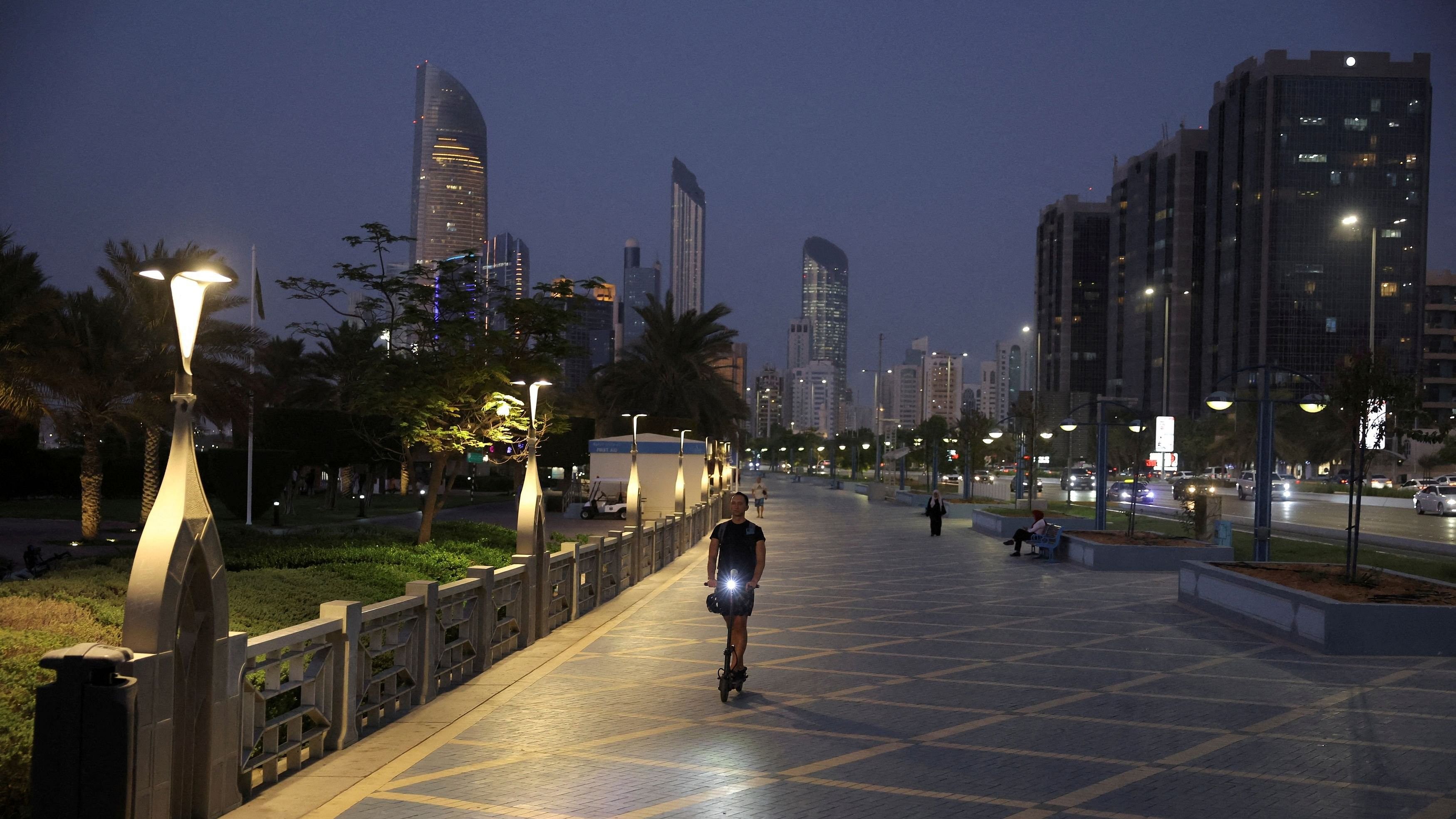 <div class="paragraphs"><p> A person rides a scooter with the skyline visible in the background, in Abu Dhabi, United Arab Emirates.</p></div>