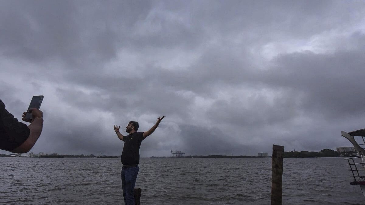 <div class="paragraphs"><p>A person gets pictures clicked in the backdrop of the sea as dark clouds engulf the sky, at Marine Drive, in Kochi.</p></div>