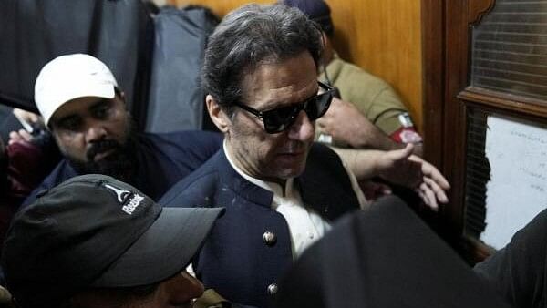 <div class="paragraphs"><p>Security officers escort Pakistan's former Prime Minister Imran Khan, as he appears in Lahore High Court.</p></div>