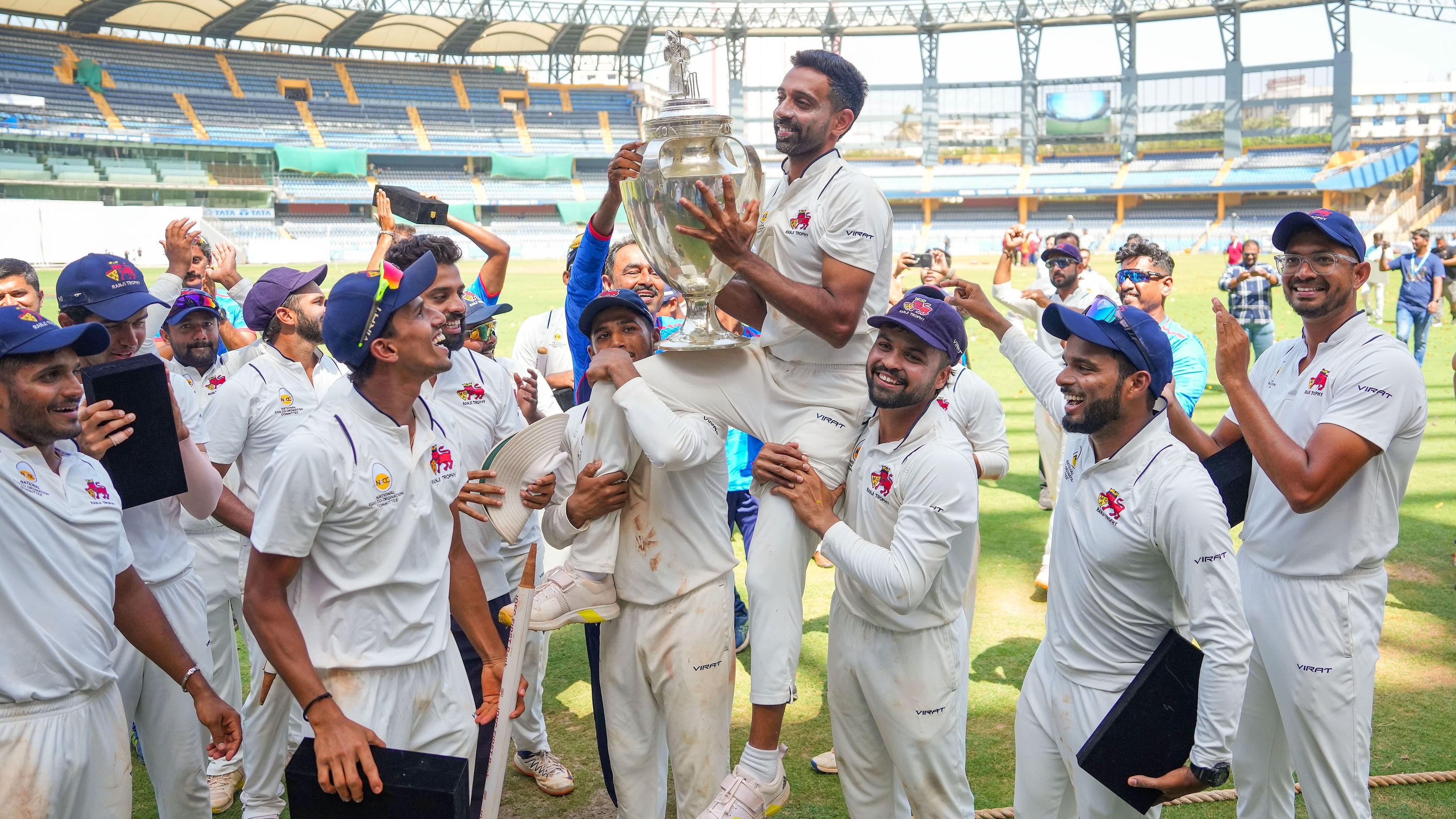 <div class="paragraphs"><p>Mumbai's Dhawal Kulkarni lifts the championship trophy after winning the Ranji Trophy final test cricket match between Mumbai and Vidarbha as he played his last match, at the Wankhede Stadium, in Mumbai, Thursday, March 14, 2024.</p></div>