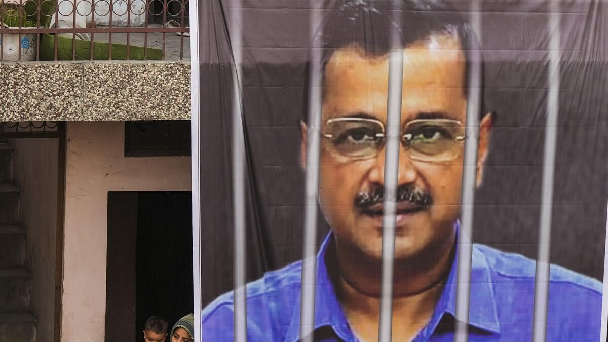 <div class="paragraphs"><p>Locals watch as a large banner of jailed Delhi Chief Minister Arvind Kejriwal hangs from the balcony of a building during an AAP roadshow for the Lok Sabha polls, in New Delhi.</p></div>