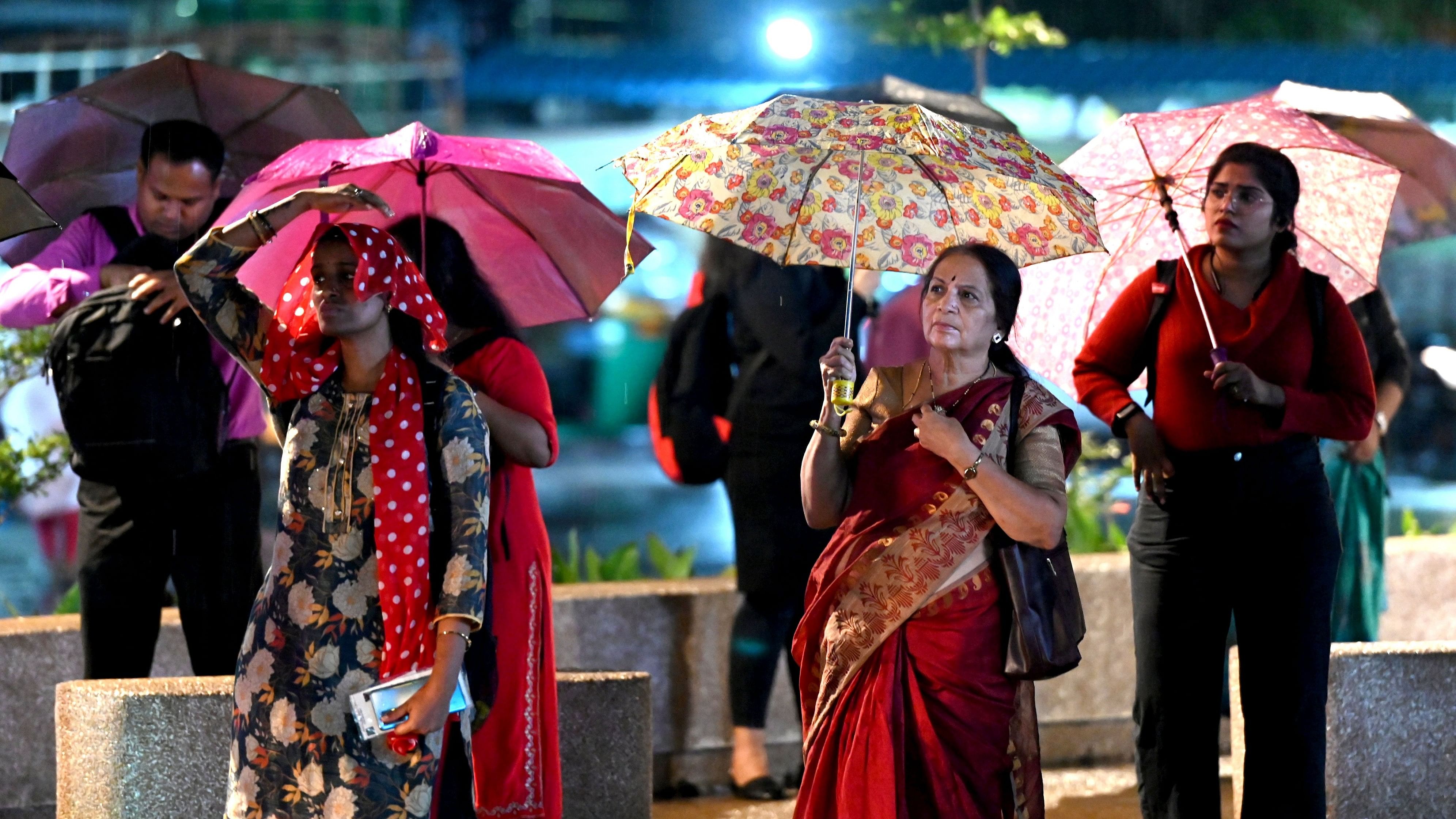 <div class="paragraphs"><p>Passengers wait for the bus at Sampige Road during the evening showers on Friday. </p></div>