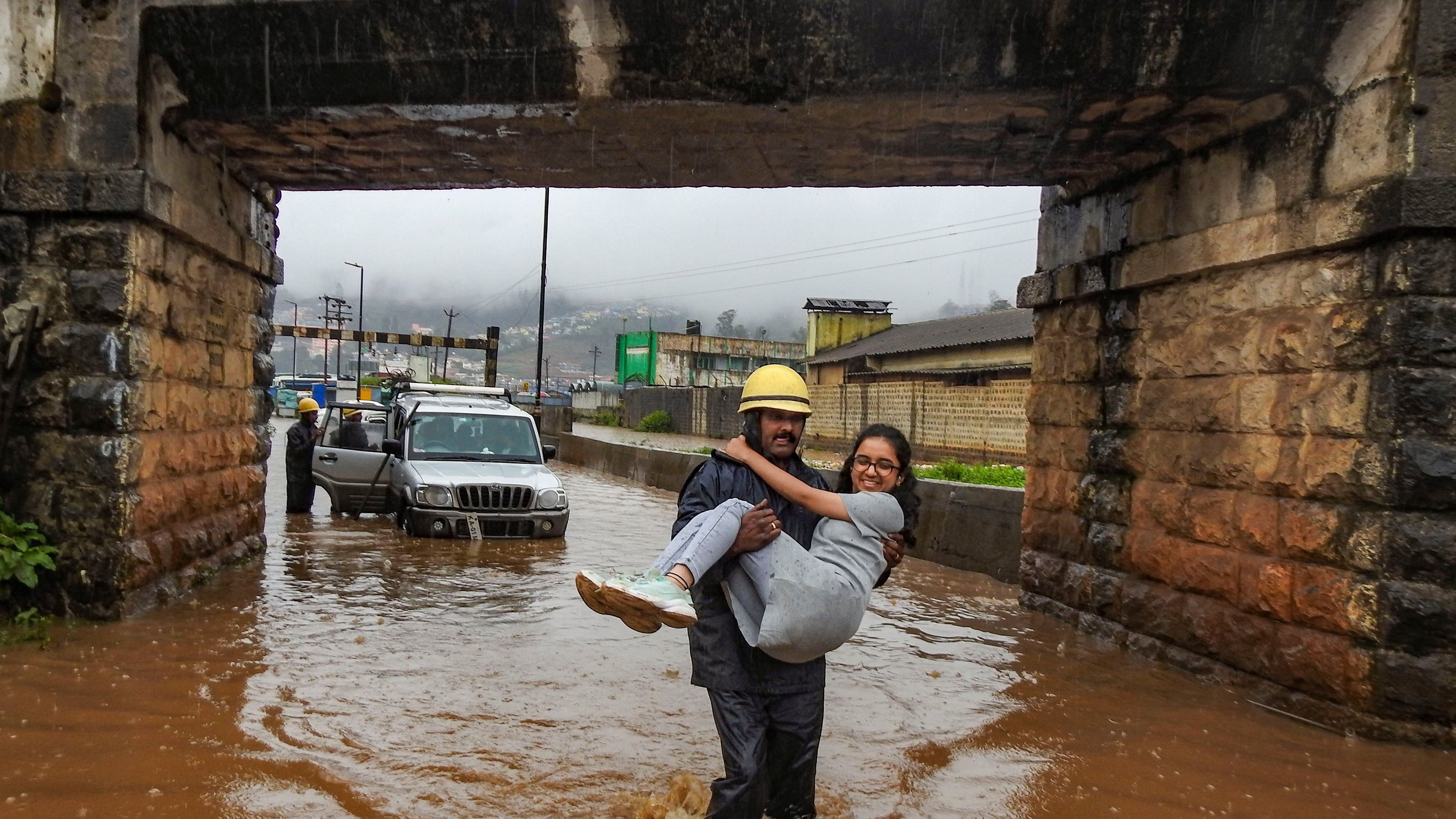 <div class="paragraphs"><p> Firefighters rescue people stuck in a vehicle on a waterlogged road, following rains, in Ooty.</p></div>