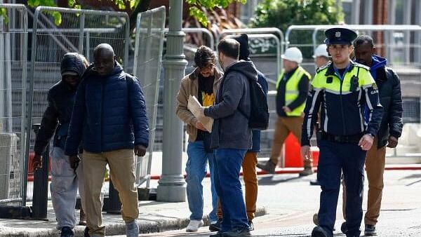 <div class="paragraphs"><p>People believed to be asylum seekers walk next to a member of the Irish Police (Garda), as Garda started to dismantle tents used by asylum seekers at the International Protection Office (IPO), where hundreds of migrants in search of accommodation have been sleeping on the streets for several months with more arriving every day, in Dublin, Ireland, May 1, 2024.</p></div>