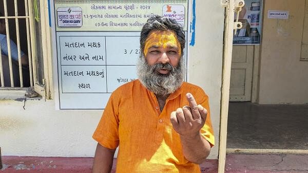 <div class="paragraphs"><p> A man shows his inked finger after casting his vote at a polling station set up in the Gir forest, Banej.</p></div>