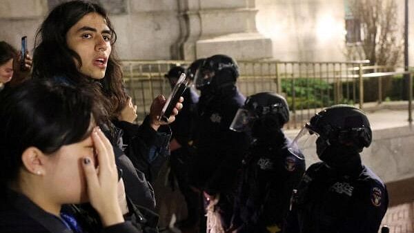 <div class="paragraphs"><p>Students react as police stand guard at Columbia University, where a building occupation and protest encampment had been set up in support of Palestinians, during the ongoing conflict between Israel and the Palestinian Islamist group Hamas, in New York City, US, April 30, 2024.</p></div>