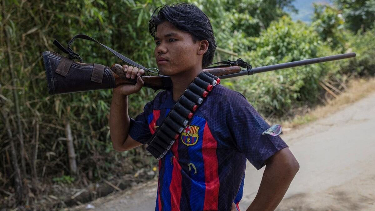 <div class="paragraphs"><p>Ngamboi, 19, an armed Kuki man, wearing a Barcelona FC shirt, stands at a checkpoint at Torbung village in Churachandpur district in the northeastern state of Manipur.</p></div>