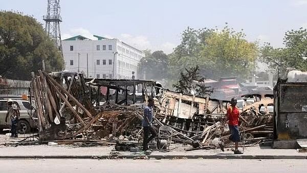 <div class="paragraphs"><p>People walk past remains of vehicles near the presidential palace, after they were set on fire by gangs, as violence spreads and armed gangs expand their control over the capital, in Port-au-Prince, Haiti.</p></div>