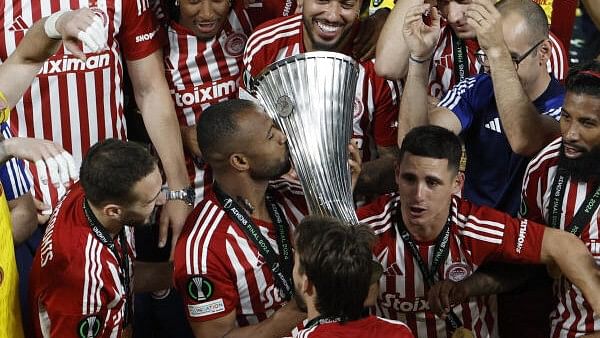 <div class="paragraphs"><p>Olympiakos' Ayoub El Kaabi kisses the trophy as he celebrates with teammates after winning the Europa Conference League.</p></div>