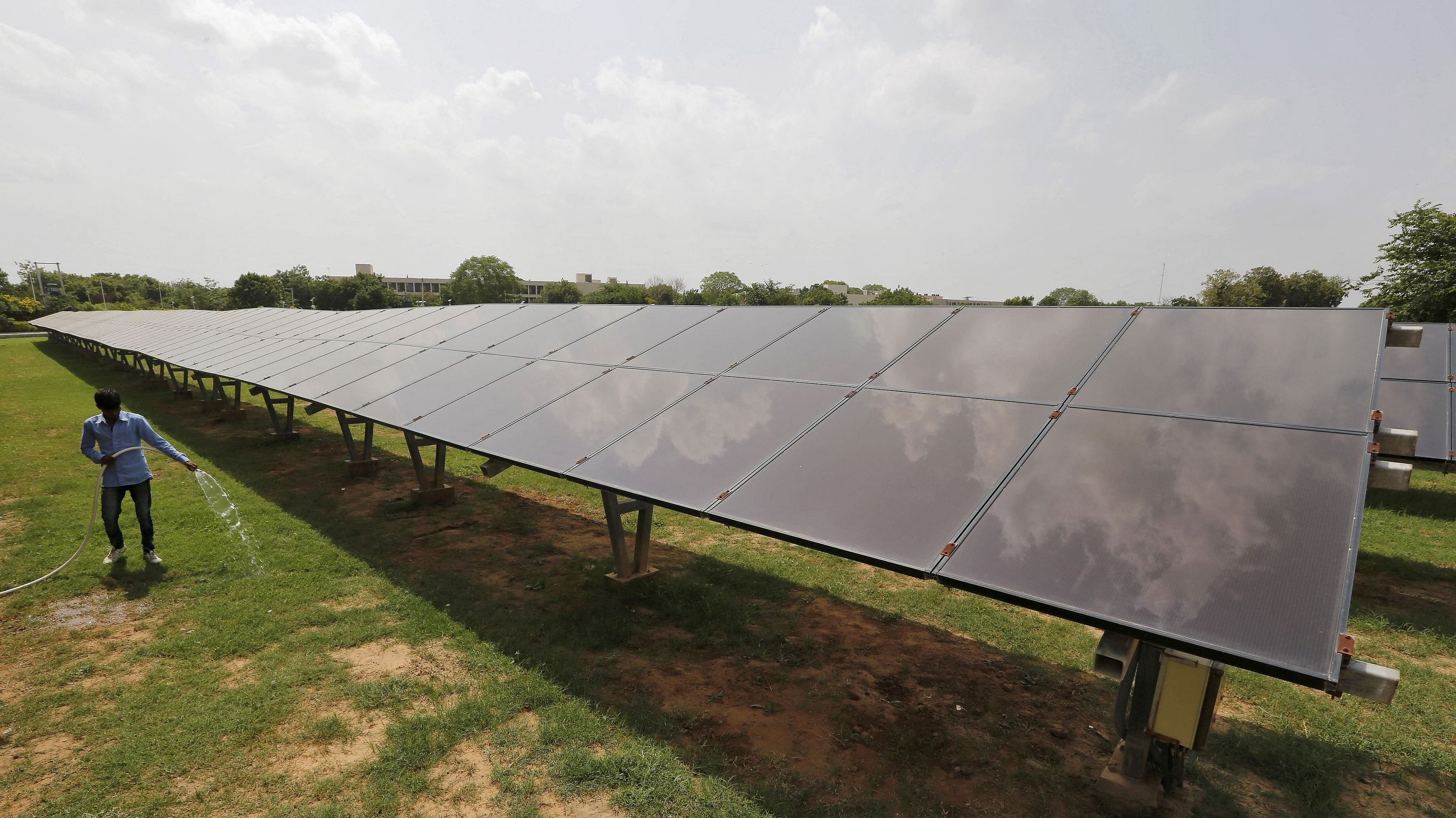 <div class="paragraphs"><p>File Photo: A worker sprays water on grass inside a solar power plant in Gujarat.</p></div>