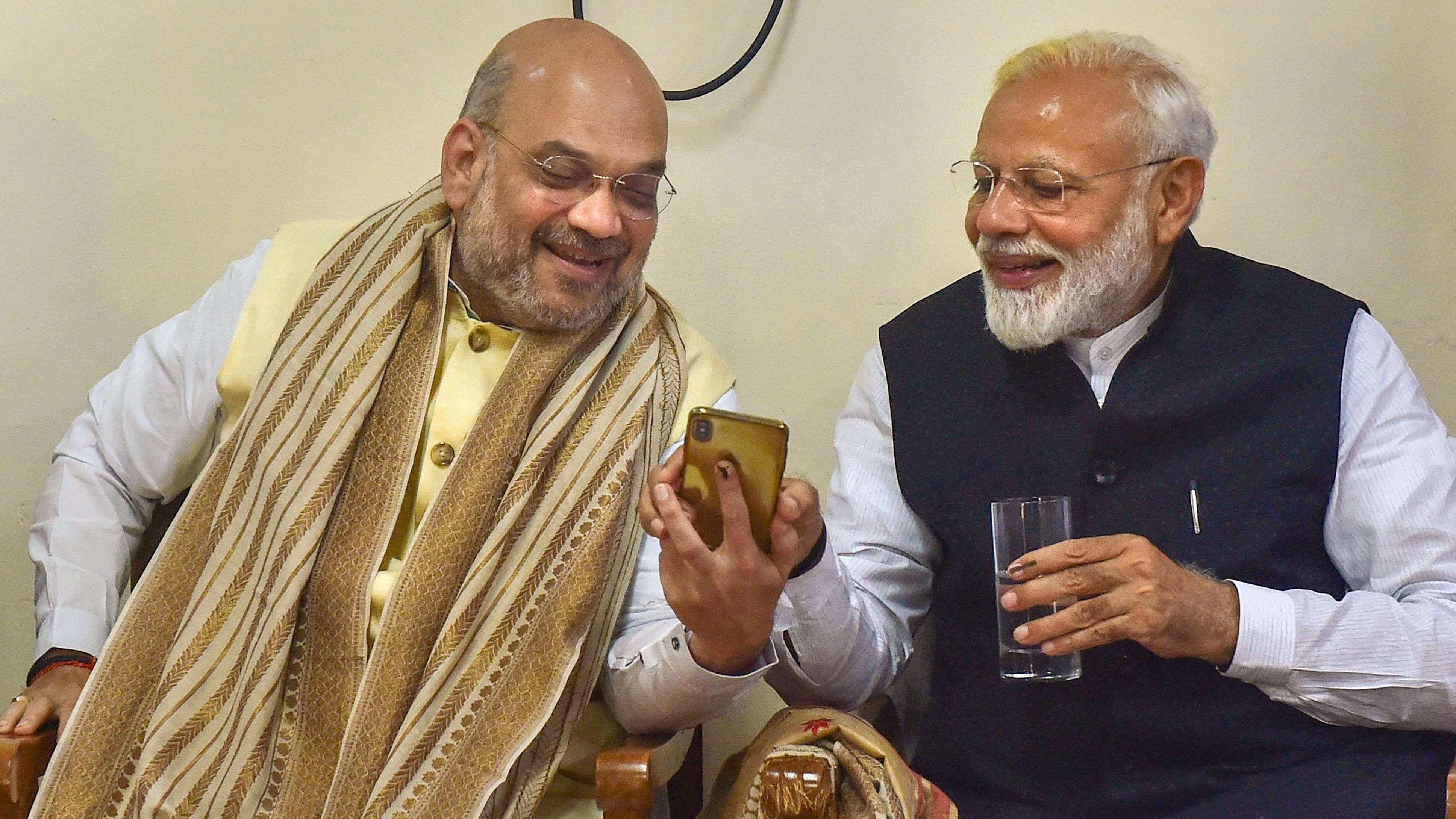 <div class="paragraphs"><p>Prime Minister Narendra Modi and Union Home Minster  Amit Shah look at a mobile phone.</p></div>