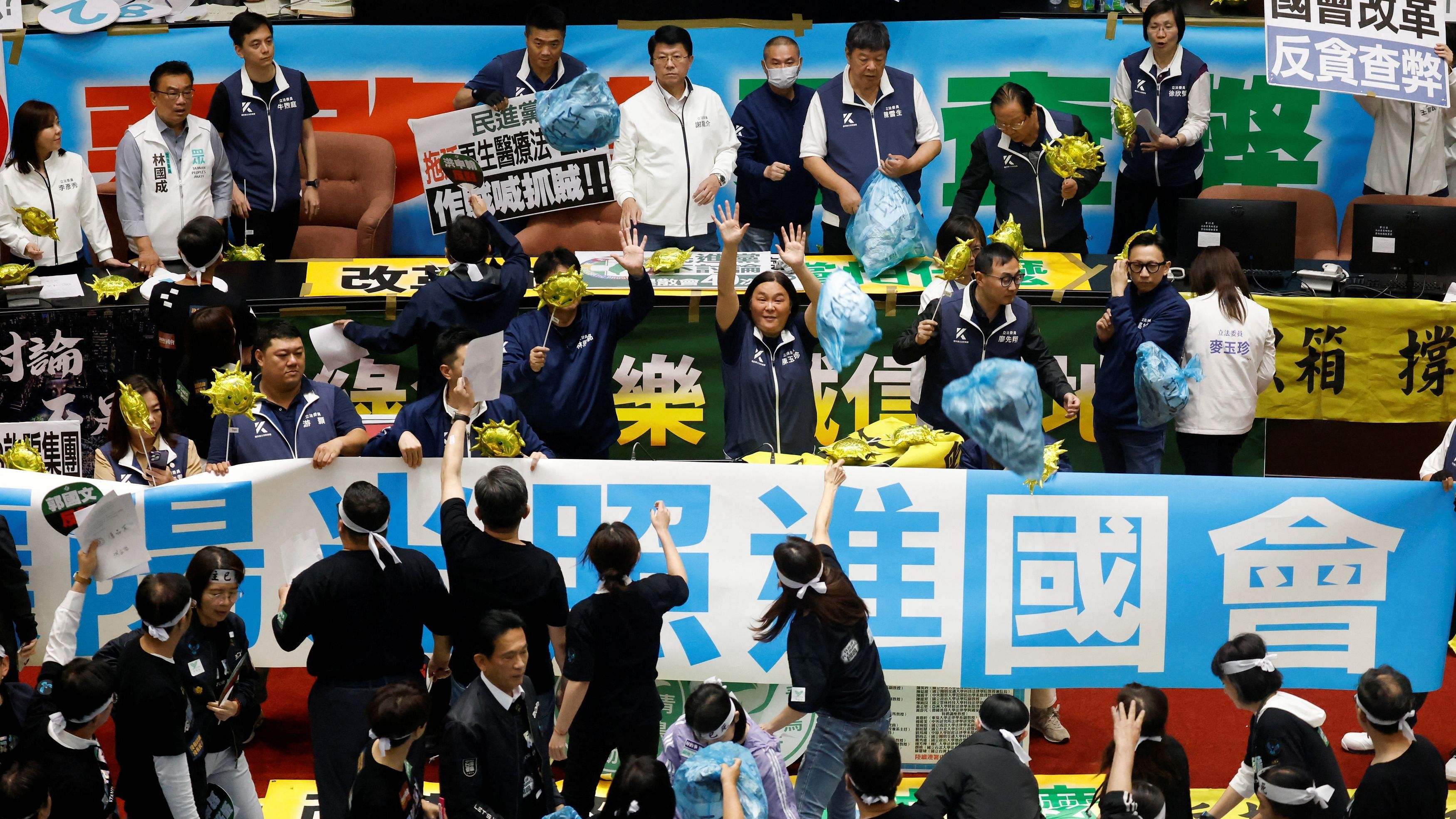 <div class="paragraphs"><p>Lawmakers from the the largest opposition party Kuomintang (KMT) try to block plastic bags  that were thrown by lawmakers from the Democratic Progressive Party (DPP), during a session at the Parliament in Taipei, Taiwan.</p></div>