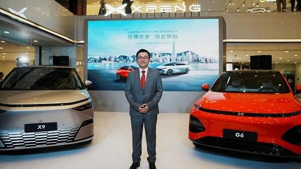 <div class="paragraphs"><p>Xpeng Co-President Brian Gu poses for a photograph standing between the Xpeng X9 and G6 vehicles during the company's debut ceremony in Hong Kong, China May 17, 2024.</p></div>