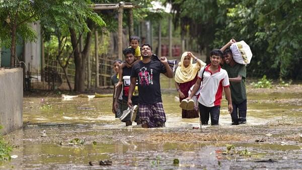 <div class="paragraphs"><p>Villagers wade through a flooded area following rains in the aftermath of Cyclone Remal, in Hojai district, Assam, Friday, May 31, 2024.</p></div>