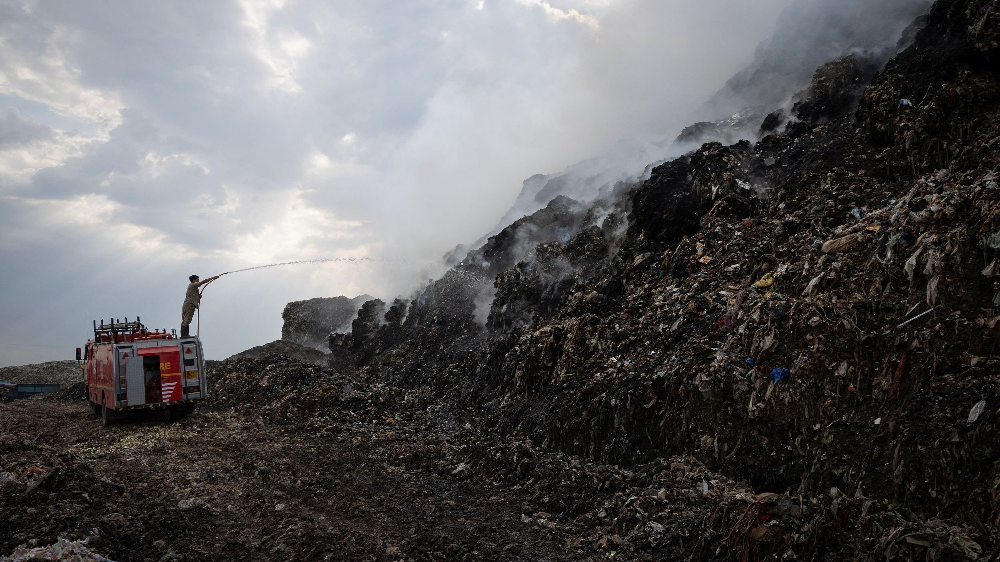 <div class="paragraphs"><p>A firefighter works to douse fire as smoke billows from burning garbage at the Ghazipur landfill </p></div>