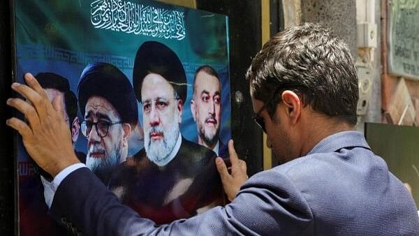 <div class="paragraphs"><p>A Houthi activist hangs a poster on the gate of the Iranian embassy as he offers condolences over the deaths of Iran's President Ebrahim Raisi and others, in Sanaa, Yemen.</p></div>