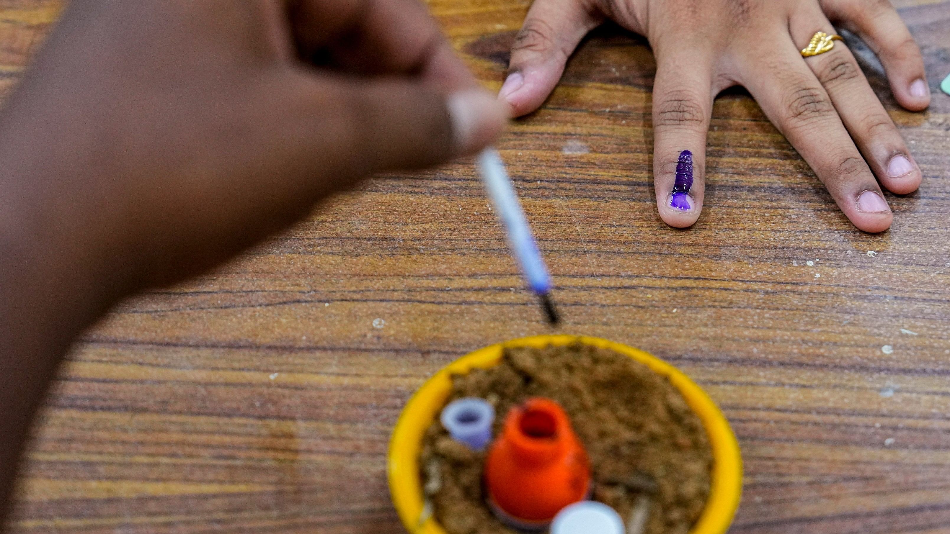 <div class="paragraphs"><p>A woman gets her finger inked after casting her vote at a polling station.</p></div>