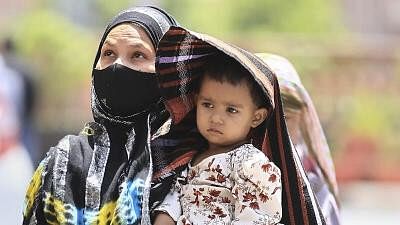 <div class="paragraphs"><p>A woman covers her child in protection from the scorching sun on a hot summer day, in Jaipur, Saturday, May 25, 2024. The India Meteorological Department (IMD) has issued a red alert for heatwave in several northern Indian cities including Rajasthan.</p></div>