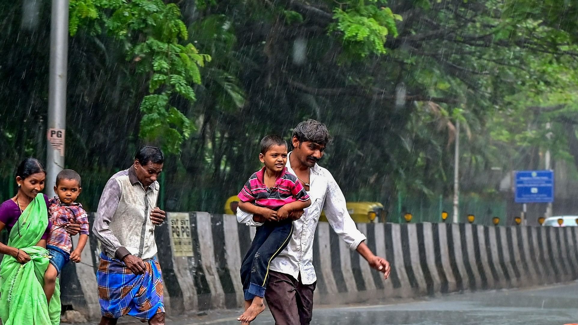 <div class="paragraphs"><p>A family crosses a road in Chamarajpet during the downpour on Sunday evening.  </p></div>