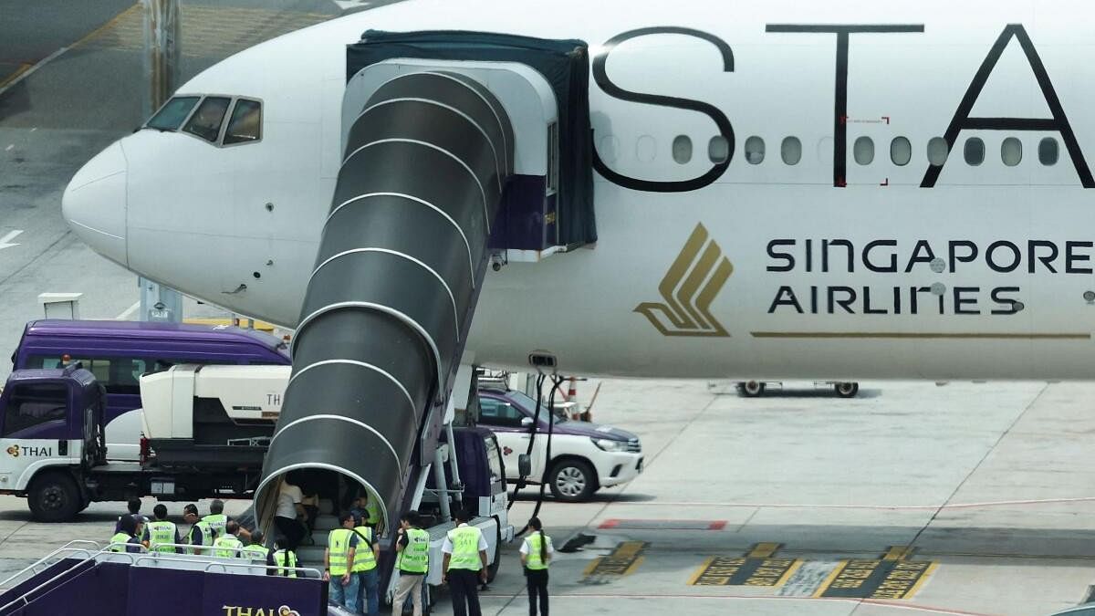 <div class="paragraphs"><p>Airport officials gather near the aircraft ladder attached to the Singapore Airlines aircraft for flight SQ321 parked on the tarmac after an emergency landing at Suvarnabhumi International Airport, in Bangkok, Thailand on May 22, 2024.</p></div>