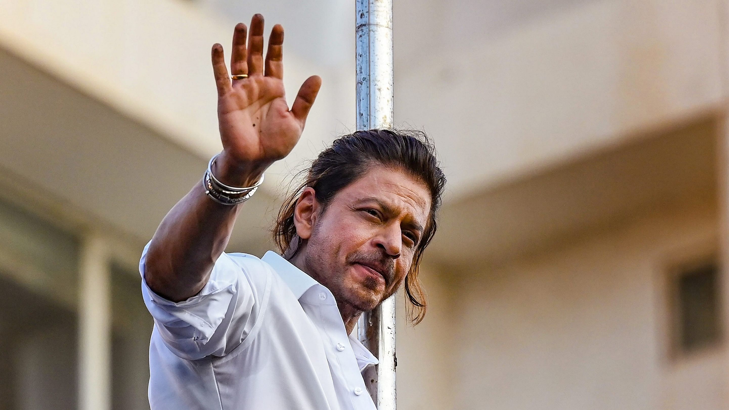 <div class="paragraphs"><p>Bollywood actor Shah Rukh Khan waves at fans gathered outside his residence.</p></div>