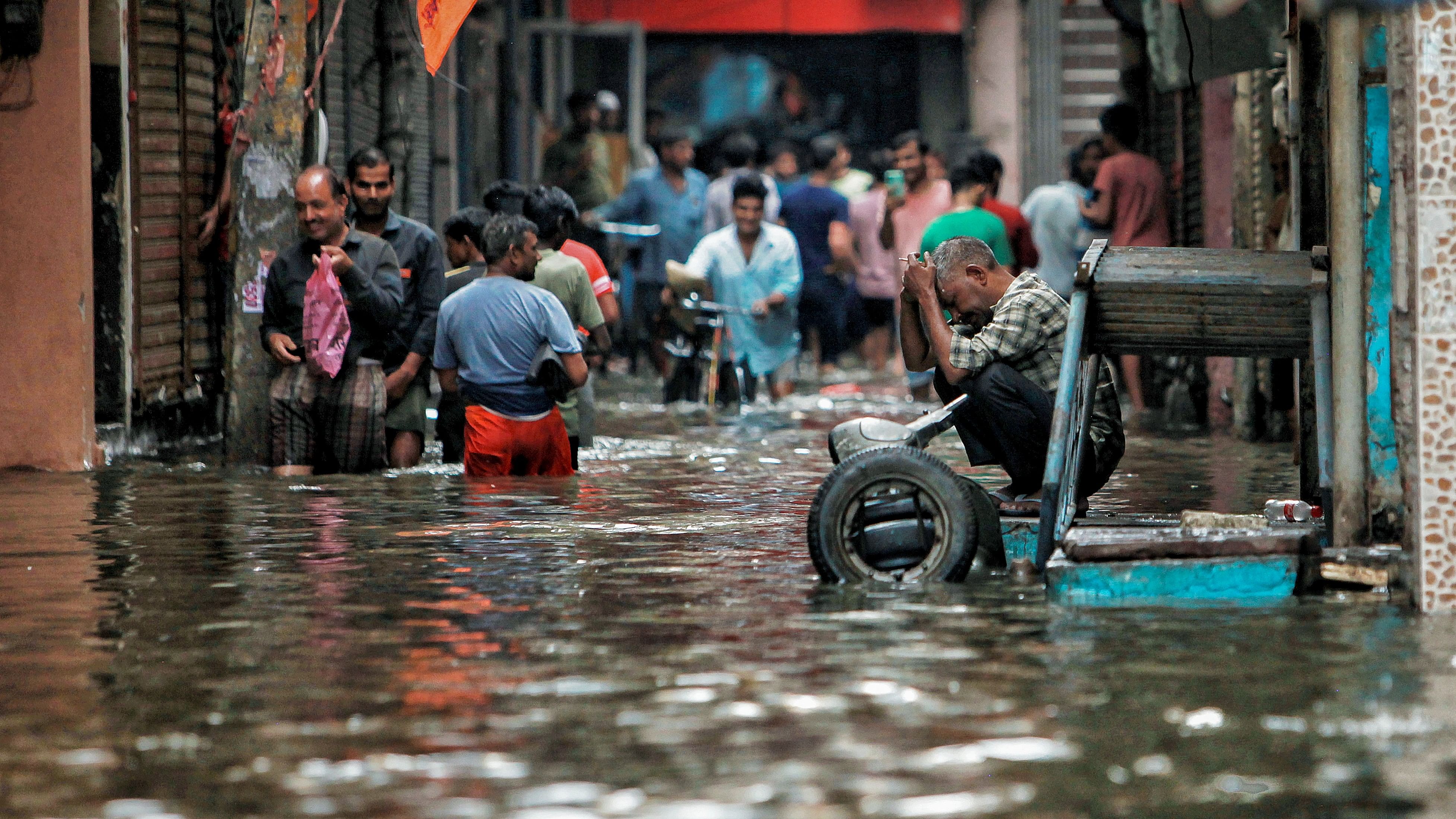 <div class="paragraphs"><p>People wade through a waterlogged road near Sarai Kale Khan area after rain, in New Delhi, on Friday.</p></div>