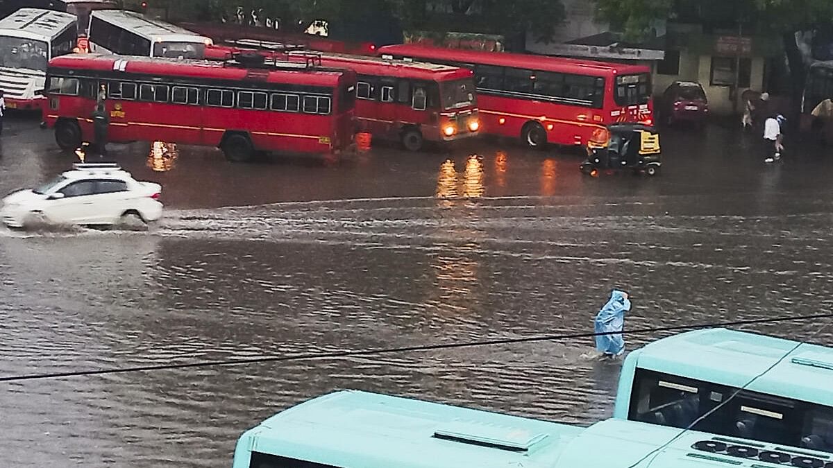 <div class="paragraphs"><p>Commuters wade through a waterlogged road amid rains, in Pune.</p></div>