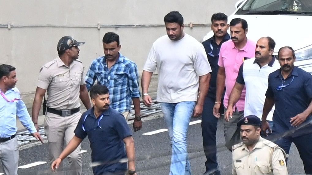 <div class="paragraphs"><p>Kannada actor Darshan Thoogudeepa (wearing a t-shirt and blue jeans) arrives for a medical checkup at Bowring and Lady Curzon Hospital in Bengaluru following his arrest in a murder case on Tuesday.</p></div>