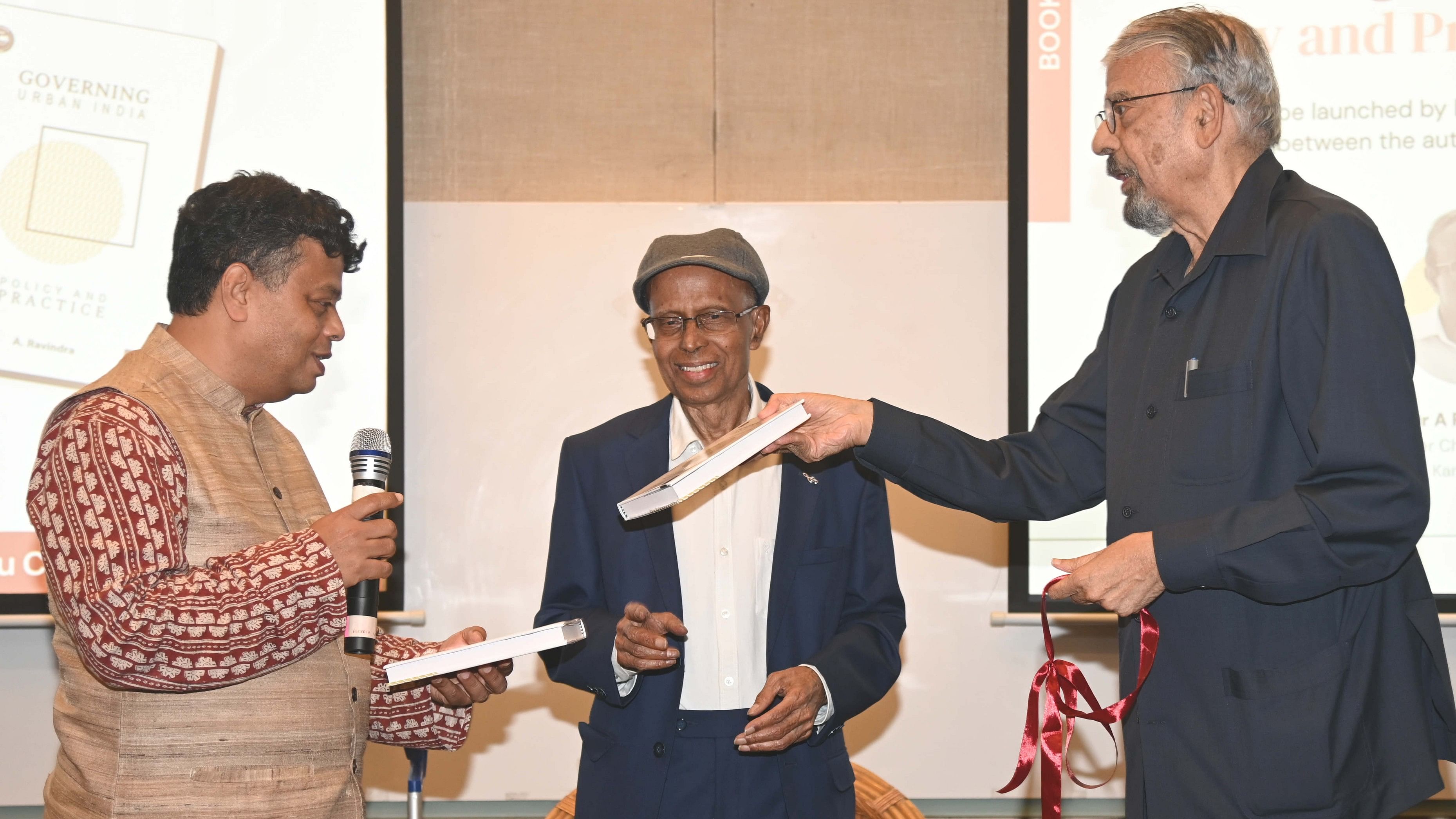 <div class="paragraphs"><p>Economist Vijay Kelkar (right) releases the book ‘Governing Urban India: Policy and Practice’, authored by former chief secretary A Ravindra (centre), at IIHS, Bengaluru, on Friday. IIHS Director Aromar Ravi is also seen. </p></div>