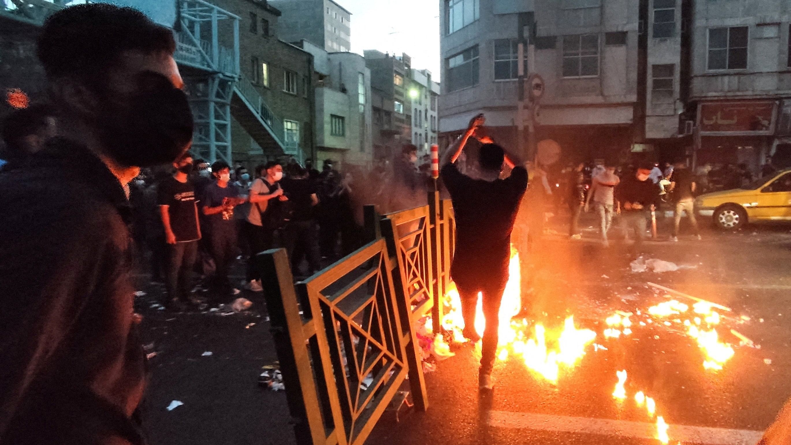 <div class="paragraphs"><p>People light a fire during a protest over the death of Mahsa Amini, a woman who died after being arrested by the Islamic republic's "morality police", in Tehran, Iran.</p></div>