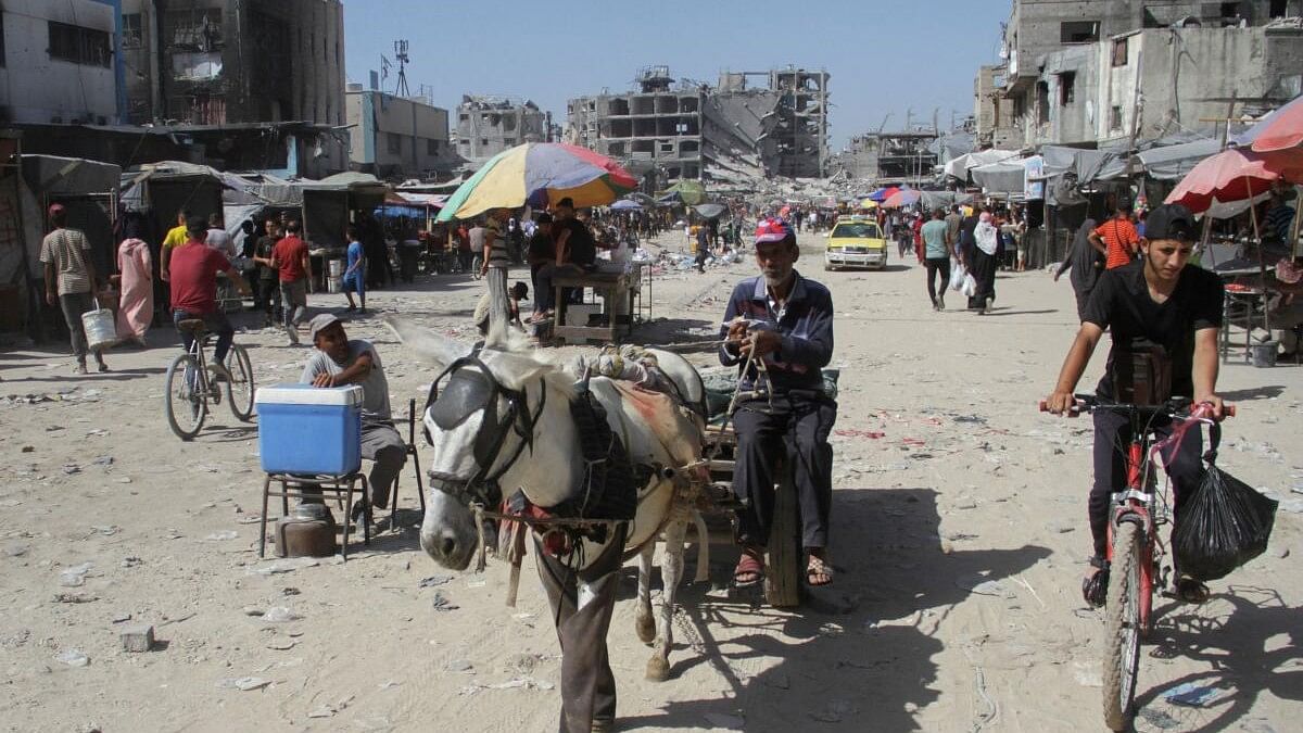 <div class="paragraphs"><p>Palestinians walk near houses destroyed in the Israeli military offensive as they struggle with food scarcity, basic necessities amid the conflict between Israel and Hamas continues, in Jabalia refugee camp, in the northern Gaza Strip, June 19, 2024.</p></div>