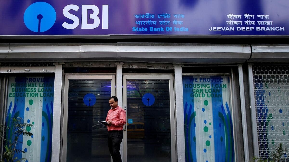 <div class="paragraphs"><p>A man checks his mobile phones in front of State Bank of India (SBI) branch in Kolkata, India.</p></div>