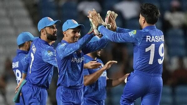 <div class="paragraphs"><p>Afghanistan's wicket keeper Rahmanullah Gurbaz, second from left, celebrates with captain Rashid Khan the dismissal of Papua New Guinea's Lega Siaka during an ICC Men's T20 World Cup cricket match at Brian Lara Cricket Academy in Tarouba, Trinidad and Tobago</p></div>