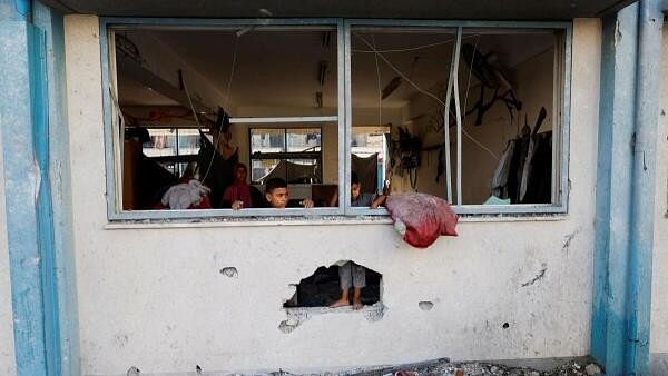 <div class="paragraphs"><p>Palestinian boys stand near the damaged windows of a classroom in a UNRWA school, after the air strike on a neighbouring house to the school in Khan Younis, in the southern Gaza Strip, June 21, 2024.</p></div>