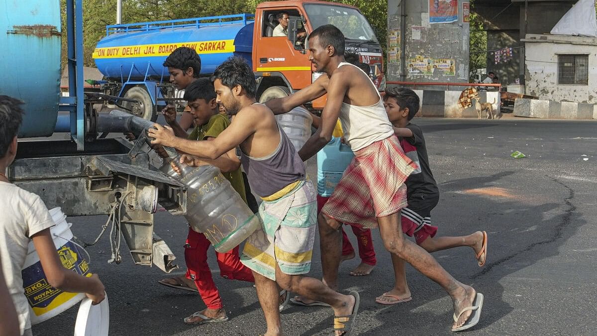 <div class="paragraphs"><p>People collect drinking water from a tanker of Delhi Jal Board on a hot summer day as water crisis continues, at a slum in Geeta Colony area, in East Delhi, Saturday.</p></div>