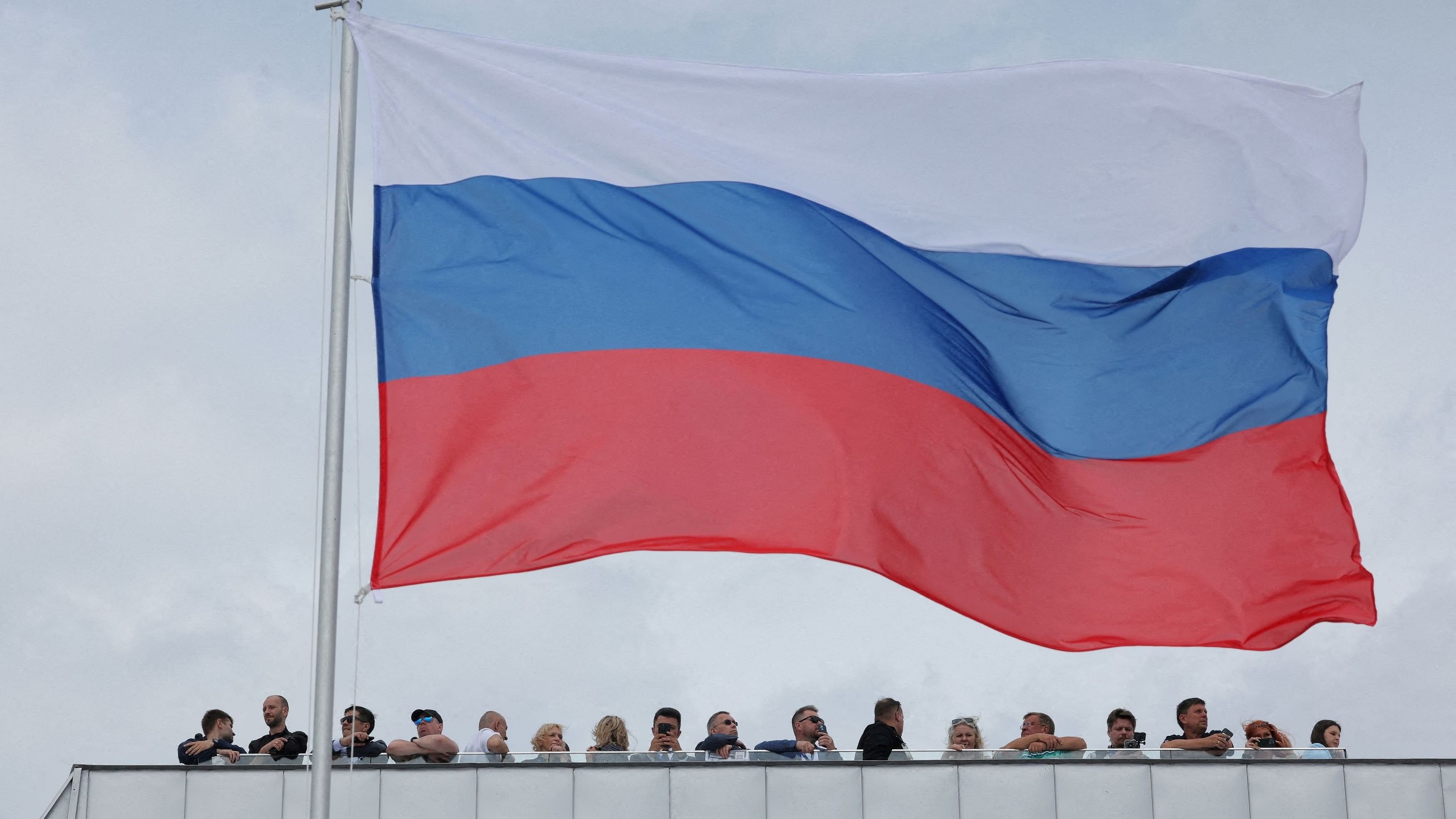 <div class="paragraphs"><p>People gather next to a large Russian flag during the International Maritime Defence Show 'FLEET-24' in Kronstadt near Saint Petersburg, Russia June 19, 2024.</p></div>