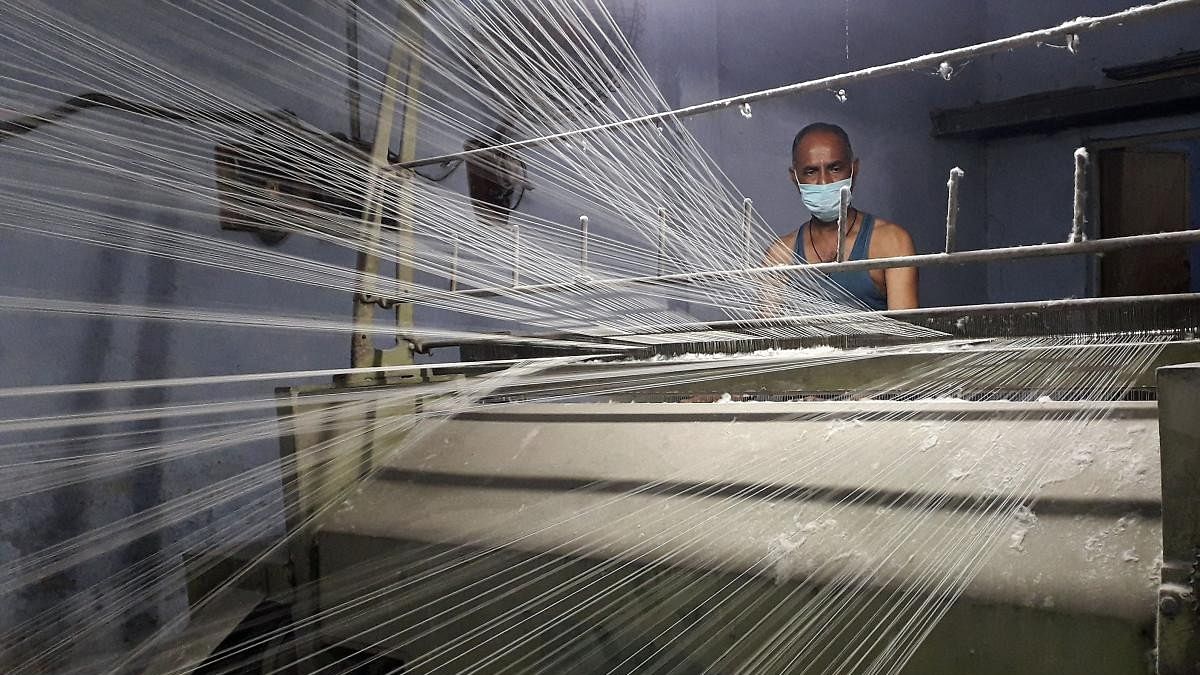 <div class="paragraphs"><p>A worker wearing a protective face mask works on a loom in a textile factory.</p></div>