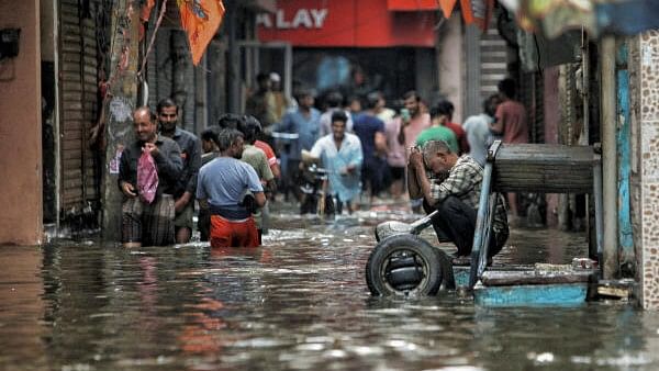 <div class="paragraphs"><p>People wade through a waterlogged road near Sarai Kale Khan area after rain, in New Delhi.&nbsp;</p></div>