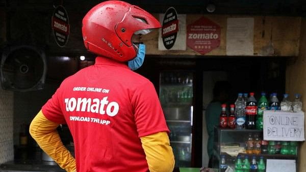 <div class="paragraphs"><p>A delivery worker of Zomato waits to collect order outside an eatery</p></div>